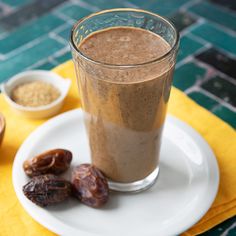 a smoothie with dates on the side and a bowl of raisins next to it