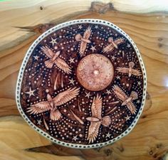 an artistically painted wooden plate with birds and stars on it