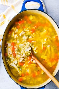 chicken noodle soup in a blue pot with a wooden spoon and napkin on the side