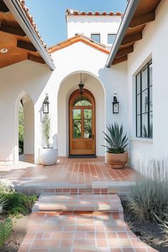 a white house with an orange door and brick walkway leading up to the front door