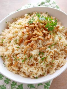 a white bowl filled with rice and nuts on top of a green cloth covered table