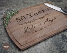 a cutting board with the words 50 years and an olive branch on it next to a knife