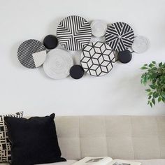 a white couch sitting next to a wall with black and white plates hanging on it