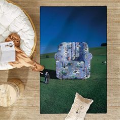 a blue chair sitting on top of a lush green field next to a white pillow