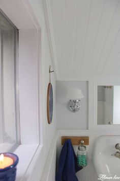 a bathroom with a sink, mirror and bathtub next to a candle on the wall