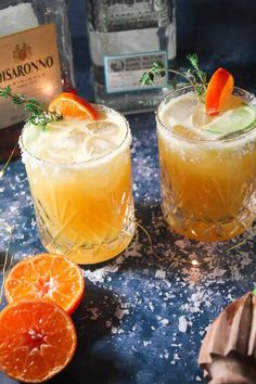 two glasses filled with orange margaritas on top of a table