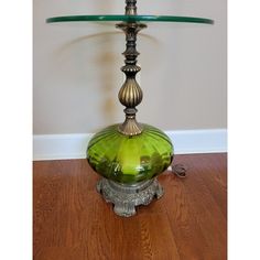 a green glass lamp sitting on top of a wooden floor