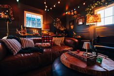 a living room filled with lots of furniture and christmas lights hanging above the couches