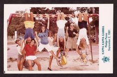 a group of young people hanging upside down on a swing set in a park, some holding onto their hands