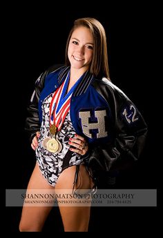 a woman posing for a photo with her medal and leather jacket over her shoulders, in front of a black background