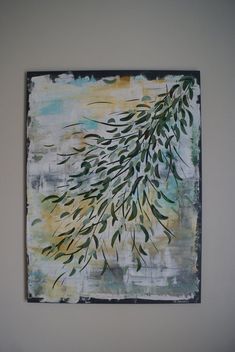 a painting hanging on the wall in a room with white walls and green leaves painted on it