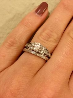 a woman's hand with two wedding rings on her left and the other hand holding an engagement ring