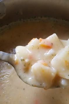 a spoon full of soup with dumplings and cheese on it's side, ready to be eaten