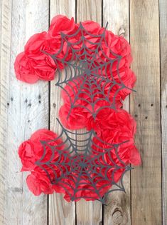 red paper flowers are arranged on a wooden surface, with the center piece cut out to look like a spider's web