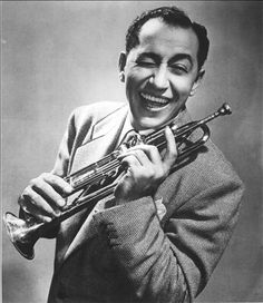 a black and white photo of a man holding a trumpet in his right hand, smiling at the camera