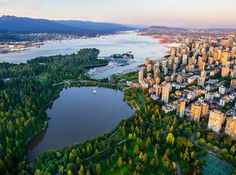 an aerial view of a large city with lots of trees in the foreground and boats on the water