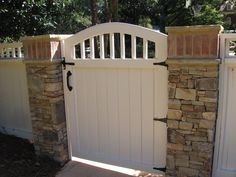 a stone wall with a white gate in front of it