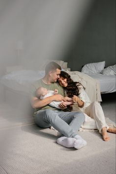 a man and woman are sitting on the floor with their baby