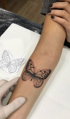 a woman's arm with a butterfly tattoo on the left side of her arm