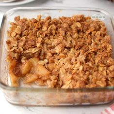 a casserole dish filled with granola and apple slices on a white table