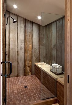 a walk in shower sitting inside of a bathroom next to a brick floored wall