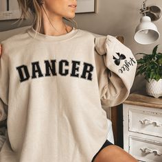 a woman wearing a sweatshirt with the word dancer on it sitting in front of a dresser