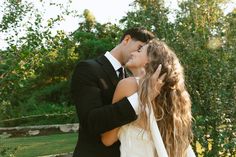 a bride and groom kissing in front of trees