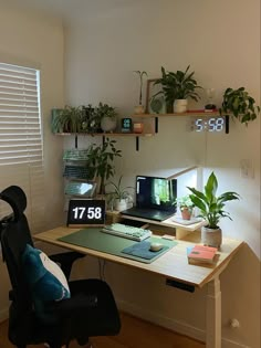 a desk with a computer and plants on it