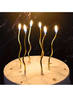 a cake with five candles on it and some gold sticks sticking out of the top