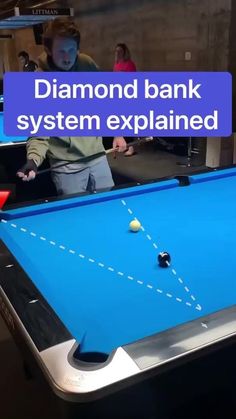 a pool table with a blue cloth on it and two people playing in the background