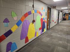 an office hallway decorated with colorful paper cutouts and cupcakes on the wall