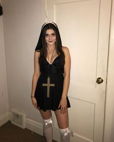 a woman dressed up as a nun standing in front of a door with her hands on her hips