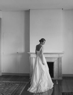 a woman in a wedding dress standing next to a fireplace