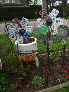 a bunch of street signs that are in the grass and some plants with flowers growing out of them