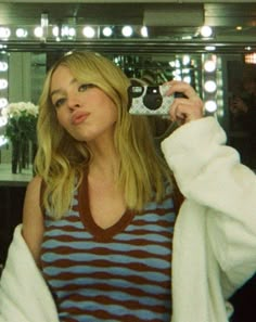 a woman taking a selfie in front of a mirror with lights on the wall