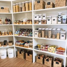 an organized pantry filled with lots of food and storage bins on white shelving