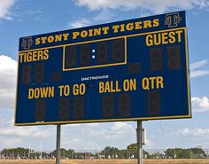 a blue and yellow scoreboard sitting in the middle of a field