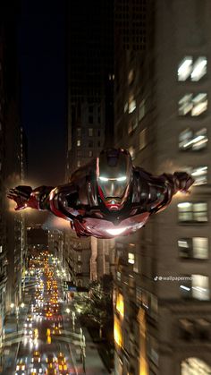 an iron man flying through the air over a city at night with lots of traffic