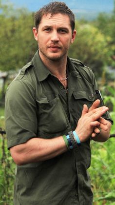 a man standing in the middle of a field with his hands together and looking at the camera