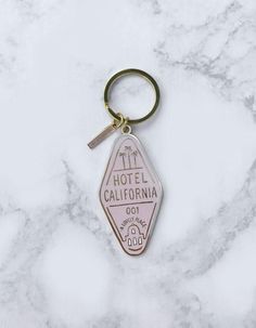 the hotel california keychain is on top of a marble counter with a white background