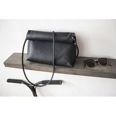 a black purse sitting on top of a shelf next to sunglasses and a pair of glasses