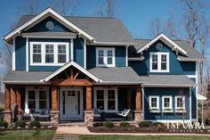 a blue house with white trim and two story windows on the front, and an attached porch