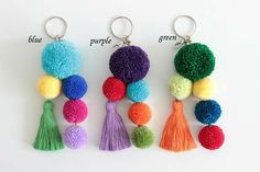 four different colors of pom pom keychains with tassels on them