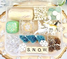 a plastic tray filled with lots of different types of toys and snowflakes on top of a wooden table