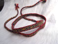 a red, yellow and blue braided necklace on a white cloth