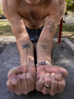 a man with tattoos on his arms sitting at a park bench