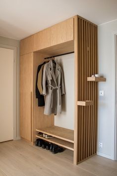 an open closet with coat and shoes in it