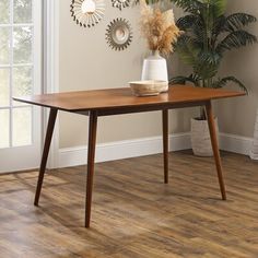 a wooden table sitting on top of a hard wood floor next to a potted plant