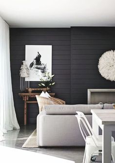 a living room with black walls and white furniture in the center, along with an art work on the wall