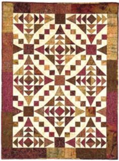 a quilted wall hanging on the side of a white wall with red and brown squares